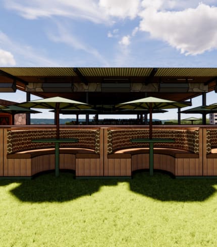 Outdoor seating area with curved wooden booths, green grass, large umbrellas, and an open-air bar in the background under a modern pavilion roof.
