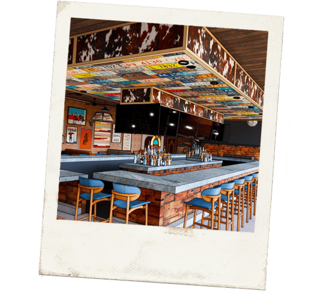 Rendered bar interior with concrete countertops, wood-paneled base, cowhide accents, and colorful license plate ceiling panels under a Polaroid-style frame.