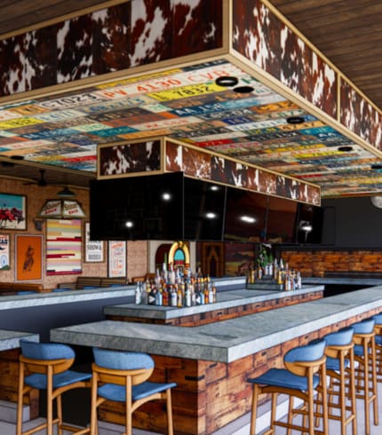 Western-themed bar interior with cowhide trim, license plates on ceiling, and fully stocked bar with stools.